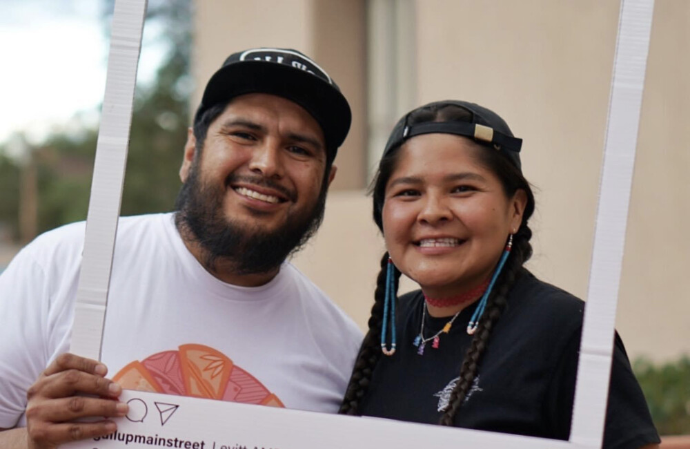 Man and woman smile for photo while holding large cut-out Instagram photo frame.