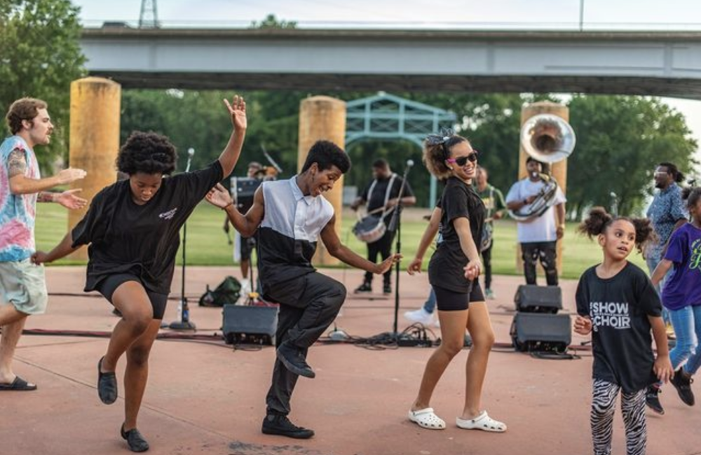 Group of young people dance to live music in outdoor venue.