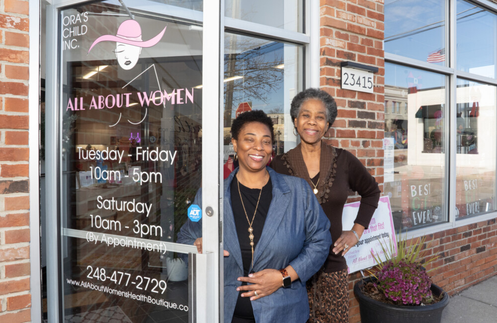 Two women proudly stand in front of their business.