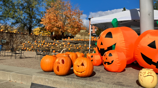 Carved pumpkins and inflatable pumpkins fill a downtown park on a sunny fall day