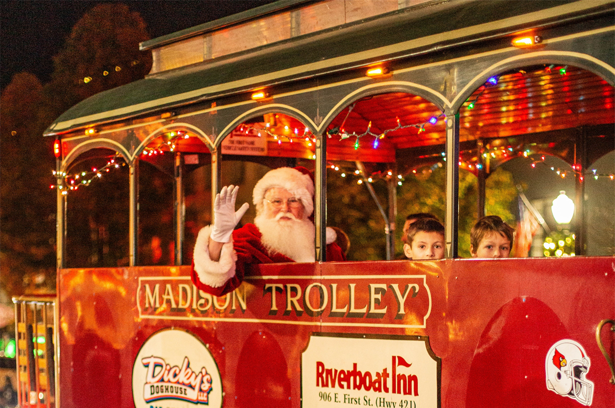 Santa riding in a festival red trolley