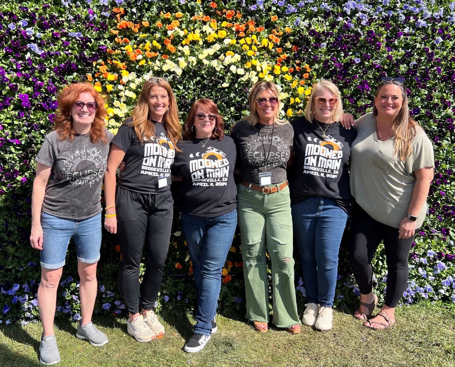 A group of people posing in front of a mural made of live flowers