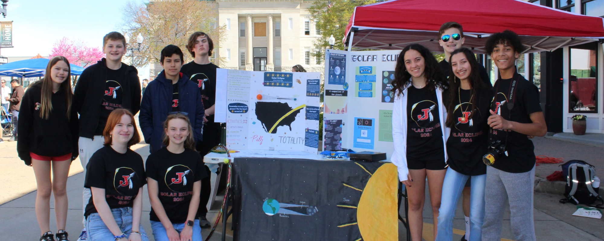 A group of kids posing with a poster board showing their science research