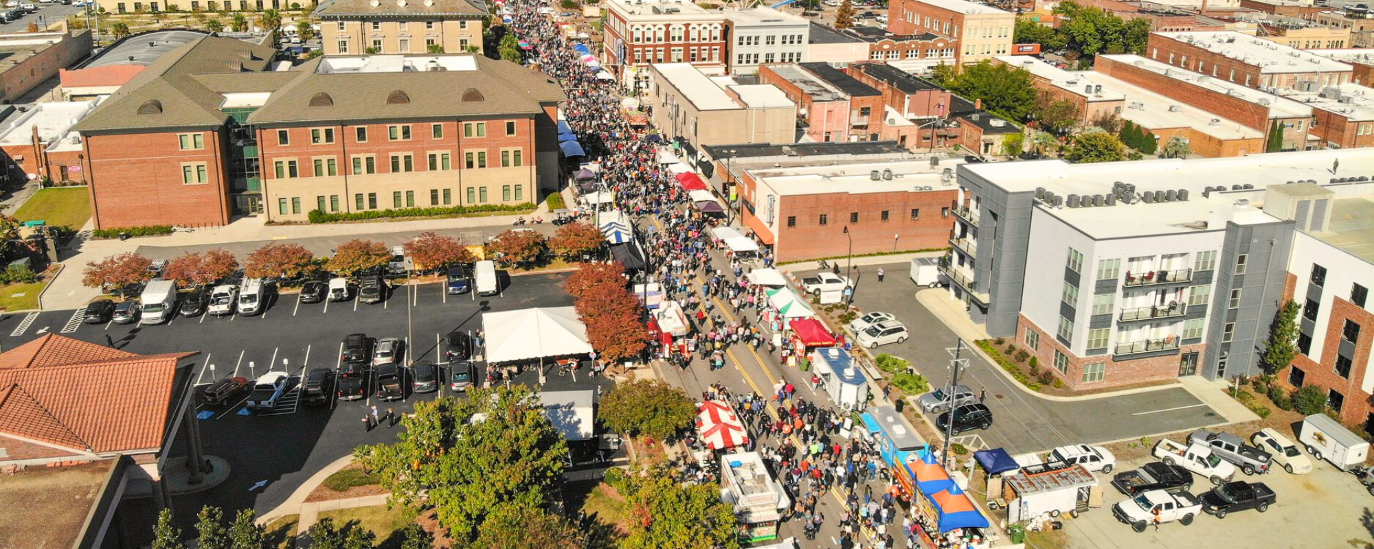 Aerial photograph of a historic downtown during a festival event with people and vendor tents lining the main street