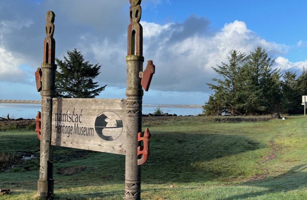 Wooden sign in front of grassy field and shoreline reading, "namscac Heritage Museum."