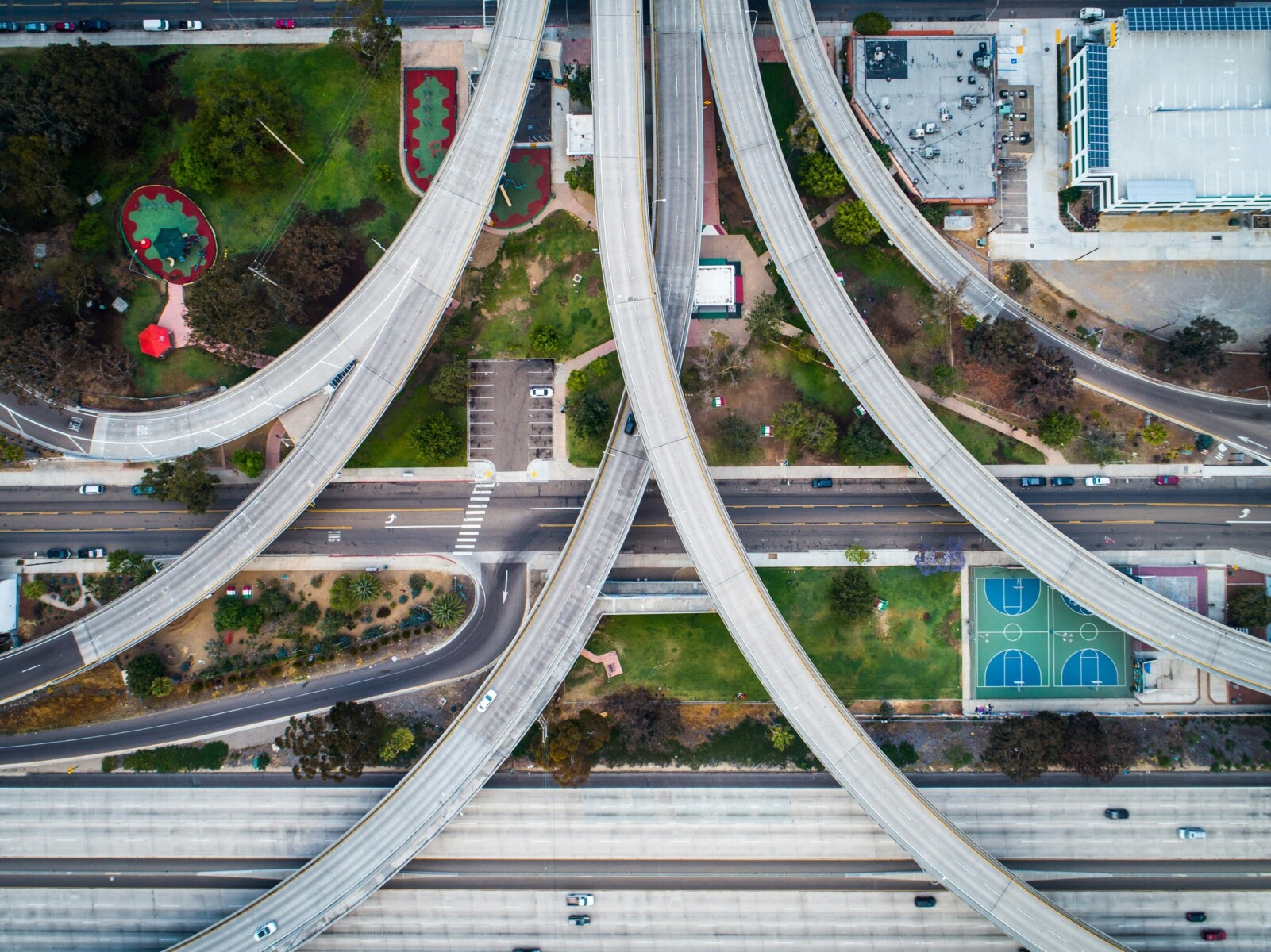 A highway overpass with a park and basketball courts underneath