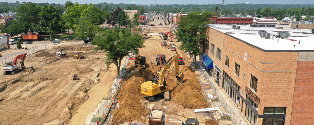 An excavator digs up dirt to create a new streetscape in a historic downtown