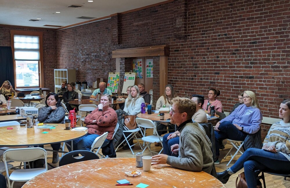Participants at a workshop sit around tables listening to a presentation