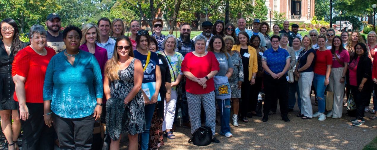 A group of people pose for a photo in a green park.