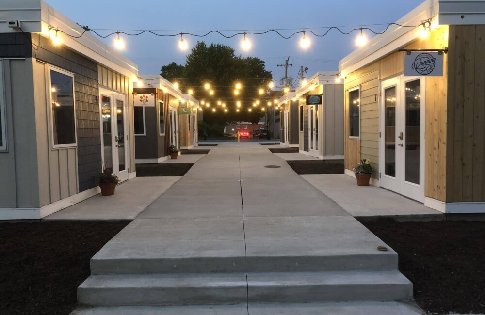 A pathway lined by small retail shops lit with overhead bulbs