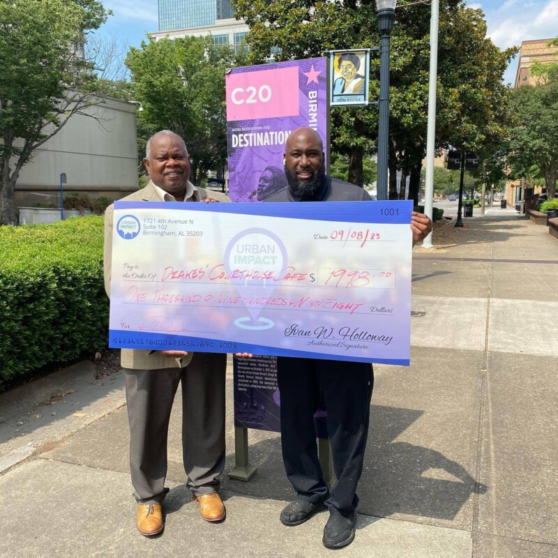 Two men hold up an oversized check.