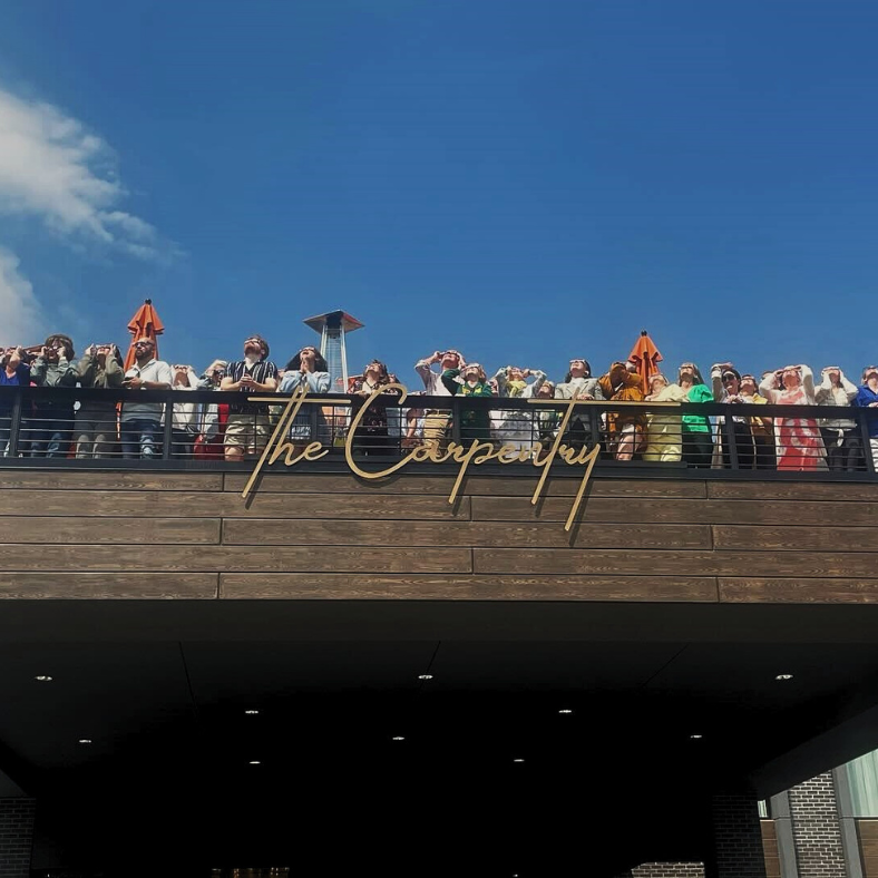 People on a rooftop look up at the sky