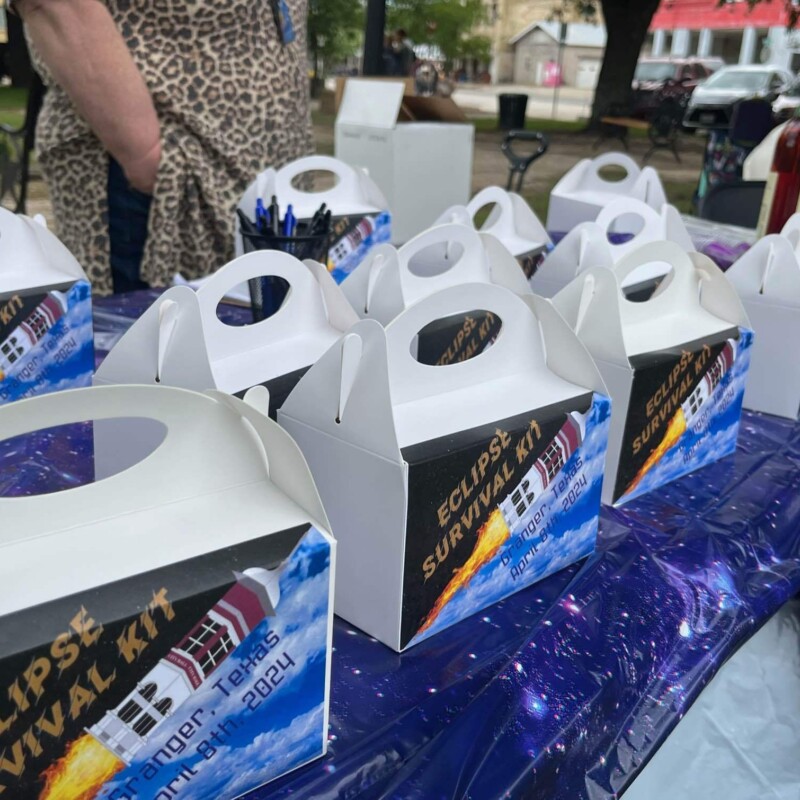 A table full of boxed labeled "Eclipse survival kit; Granger, TX"