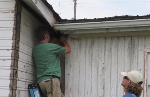 Two men work on repairs to the exterior of the historic building