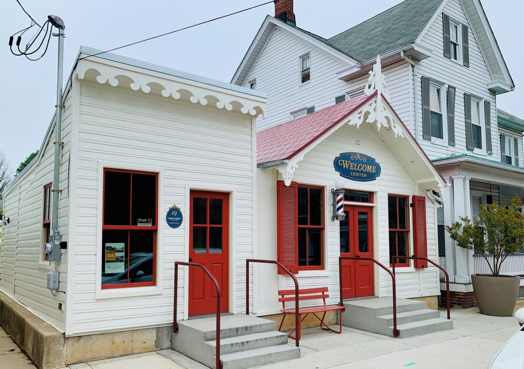 Completed rehabilitation of the historic structures with white paint, decorative woodwork, red shutters and doors, and the Main Street sign