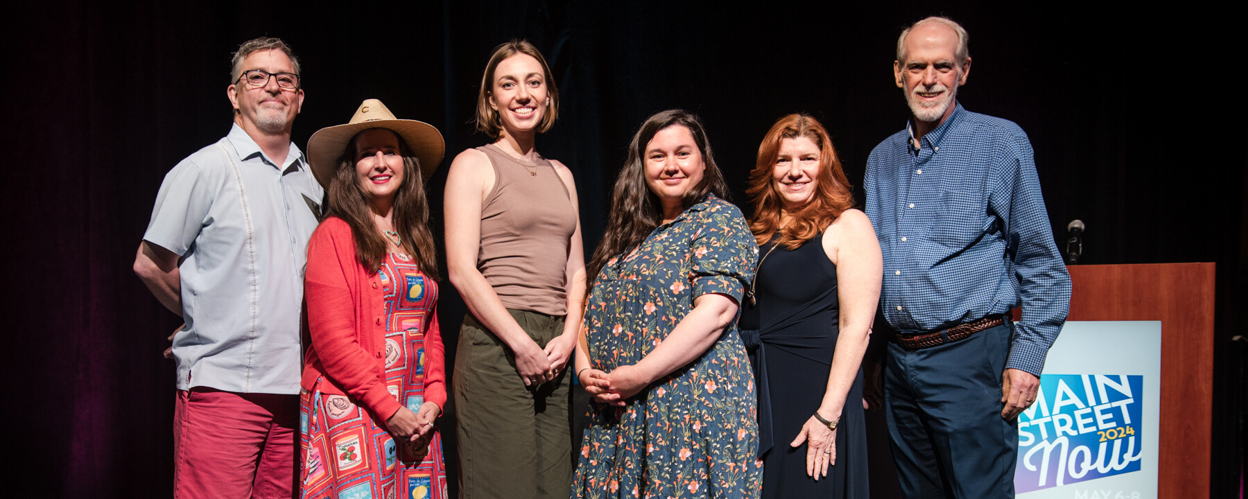 Group of people standing shoulder to shoulder on a stage.