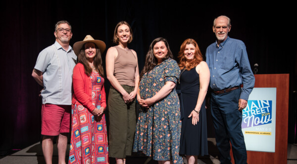 Group of people standing shoulder to shoulder on a stage.