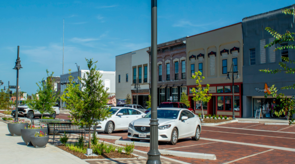 Downtown streetscape with trees, a brick road, and historic buildings