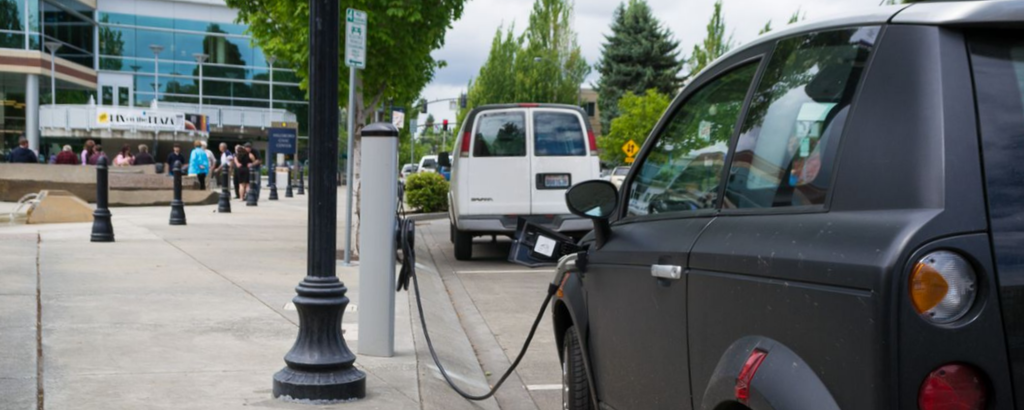 A car parked curbside while plugged into an electric vehicle charger