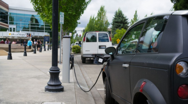 A car parked curbside while plugged into an electric vehicle charger