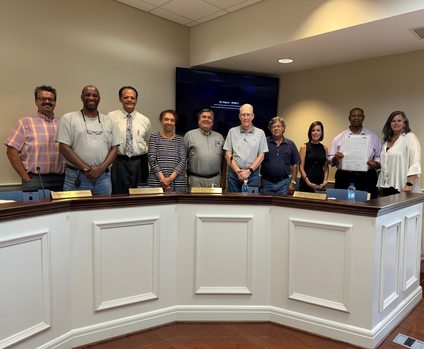 A group of people stand behind a city council desk