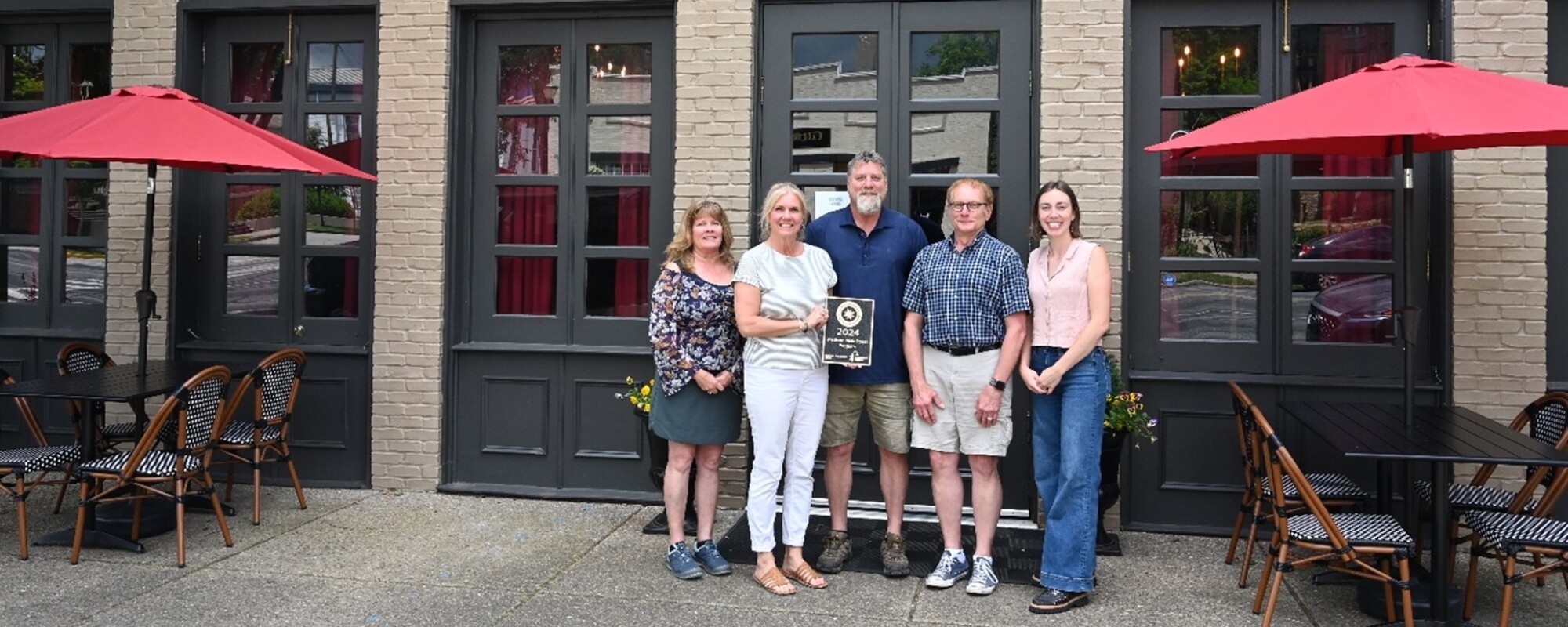 A group of people pose in front of a downtown restaurant holding the GAMSA plaque