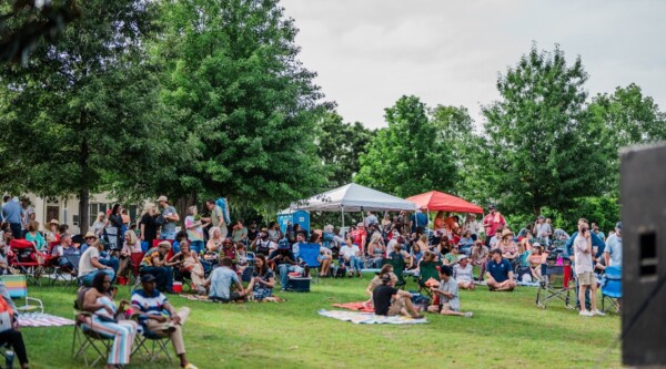 People sitting on chairs and picnic blankets at an outdoor concert