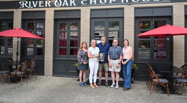 A group of people pose in front of a downtown restaurant holding the GAMSA plaque