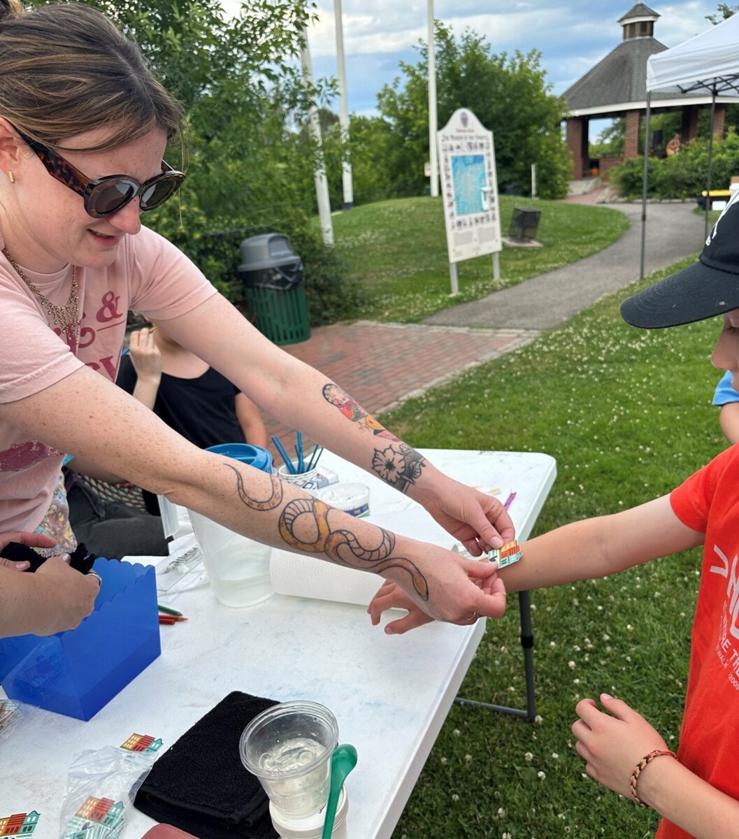 A volunteer puts a Heart of Biddeford sticker on a boy's arm