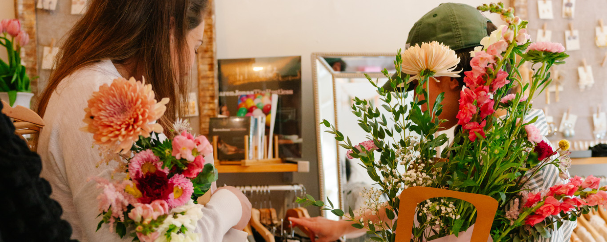 Two flower crawl participants hold their bouquets while they browse the merchandise in a participating retailer.