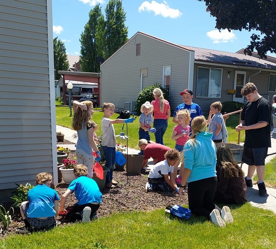 Students help spread mulch in a garden bed at an apartment complex