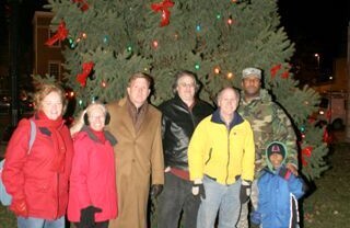 Seven people standing in front of an outdoor Christmas tree