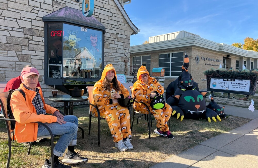 People dressed up in orange and Halloween onesies handing out candy outside their small business