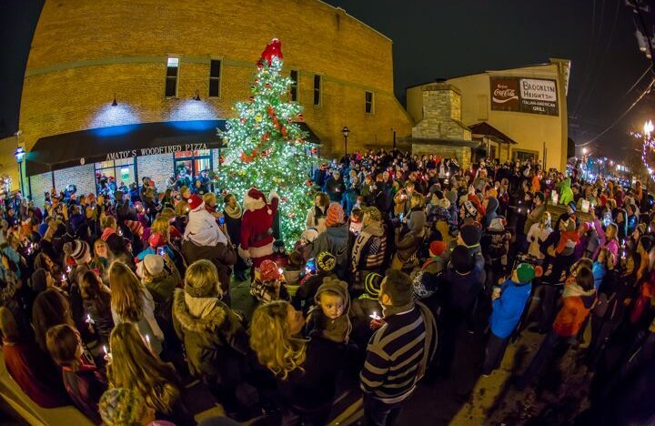 A downtown street packed with people watching a Christmas tree lighting