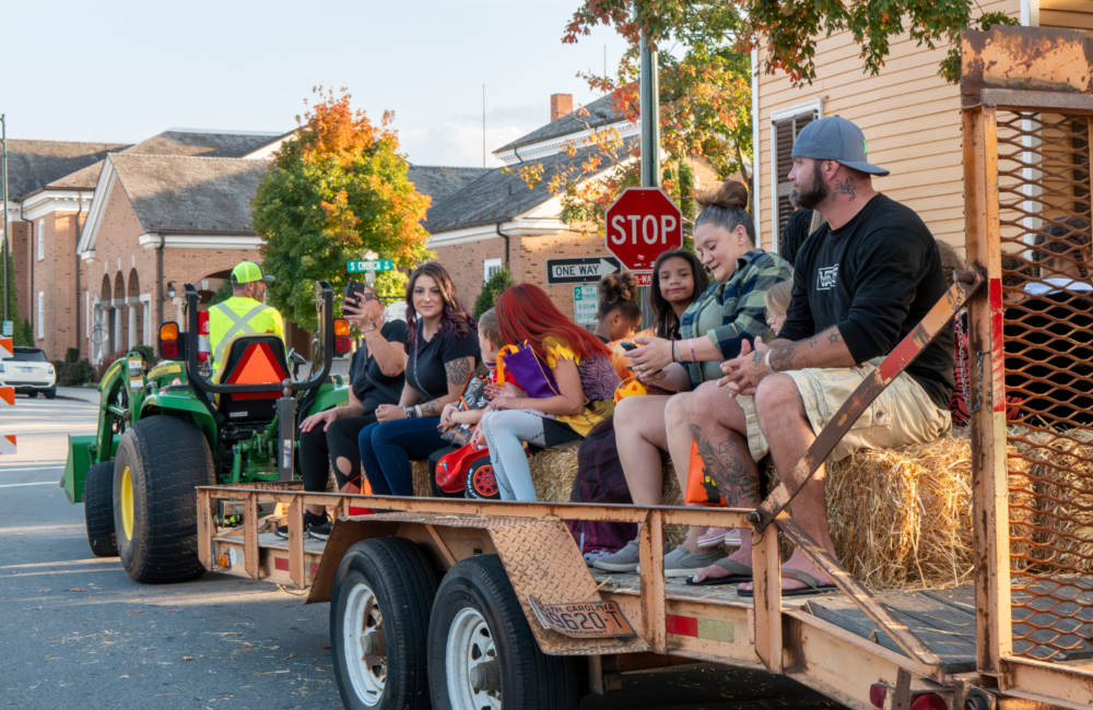 People riding on hay bales on a trailer pulled by a tractor