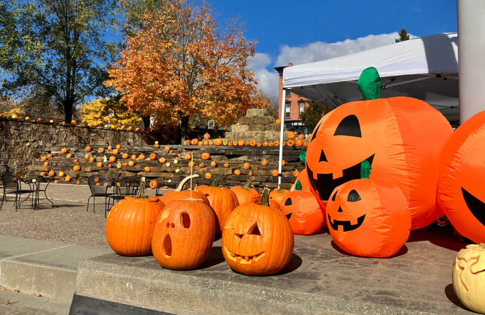 Carved pumpkins and inflatable pumpkins fill a downtown park on a sunny fall day