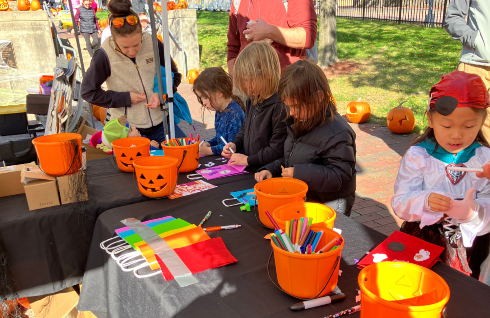 Kids in costumes decorating paper bags