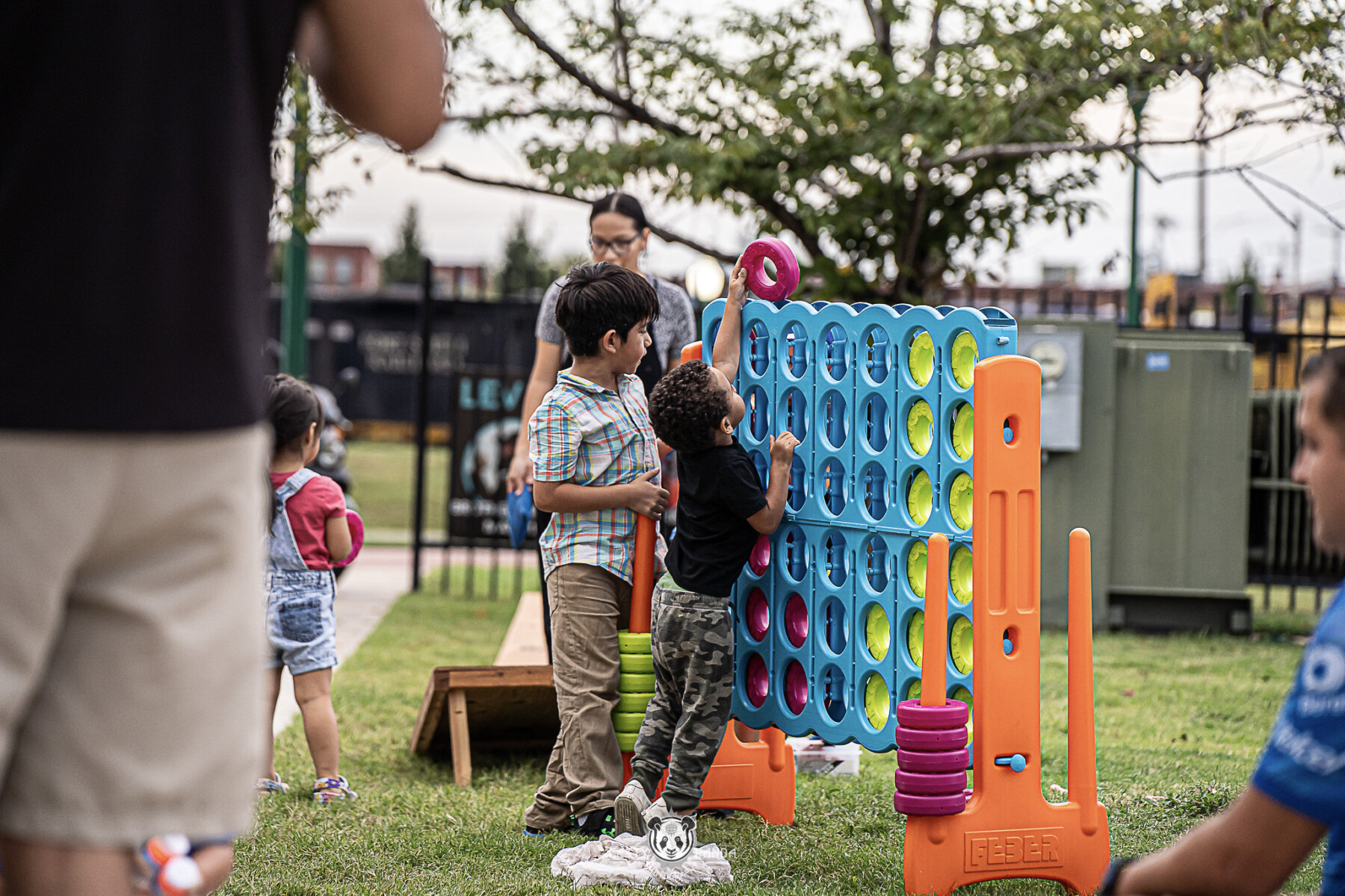 Two young children play with giant Connect Four game on outdoor lawn.