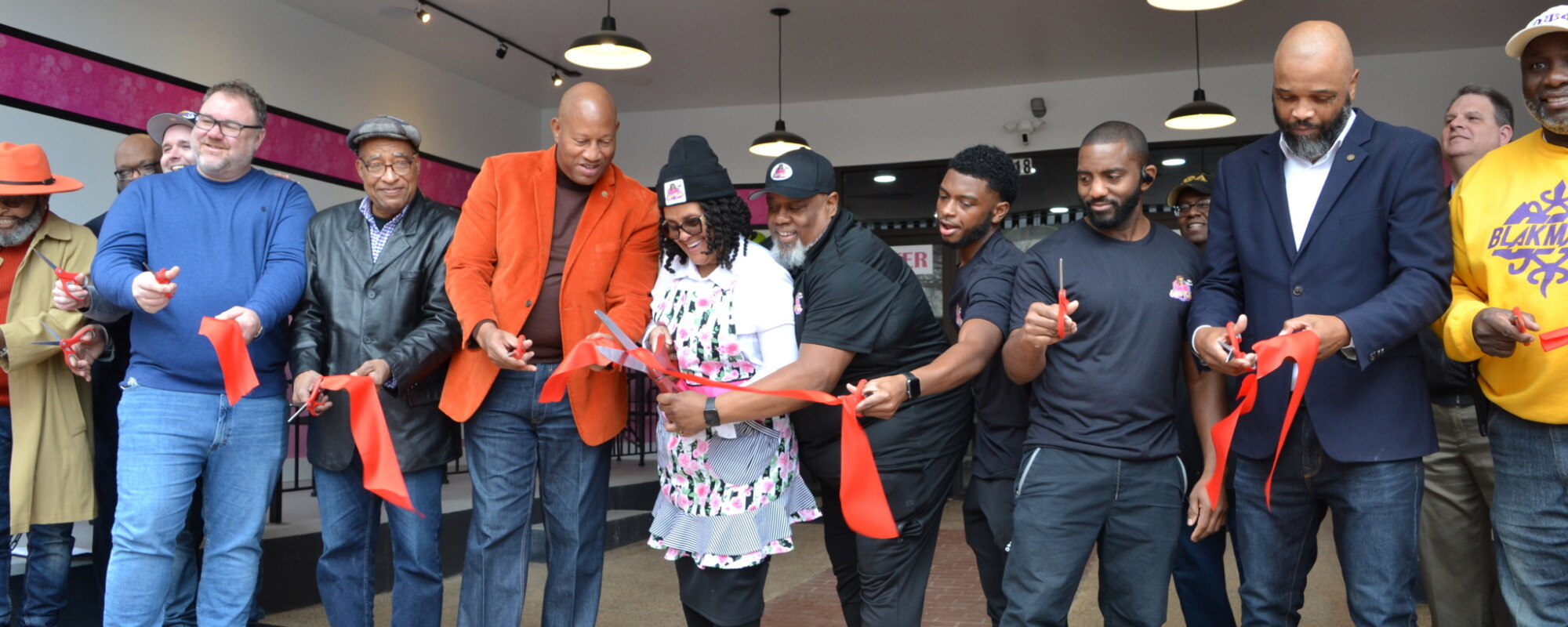 People holding lengths of red ribbon at a ribbon cutting for a small business