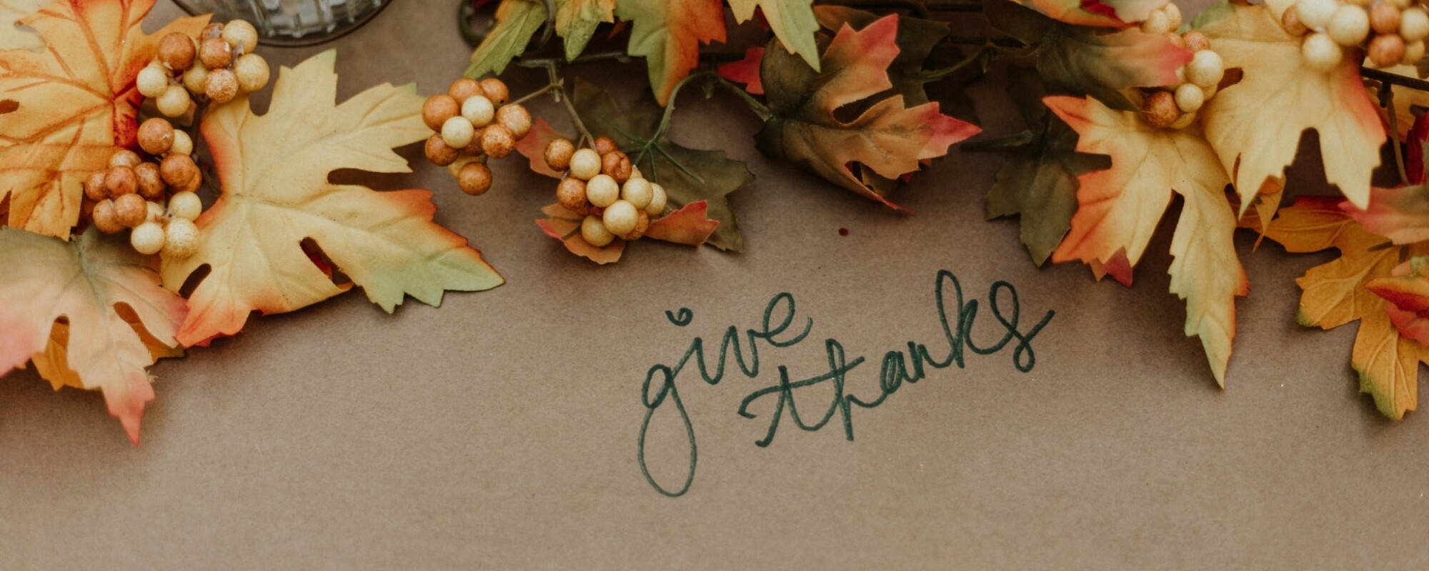 Fall leaves on a table with the words "give thanks"