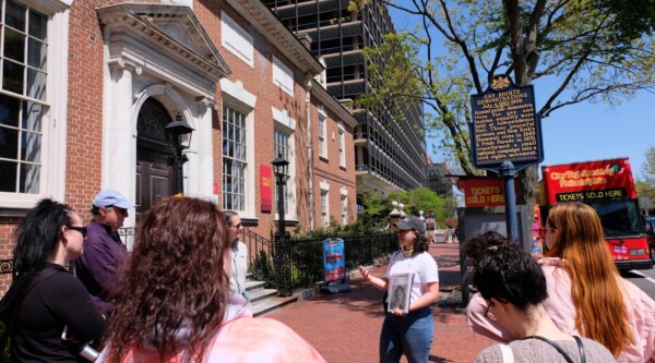 A tour group visits a gay rights demonstration a historic marker.