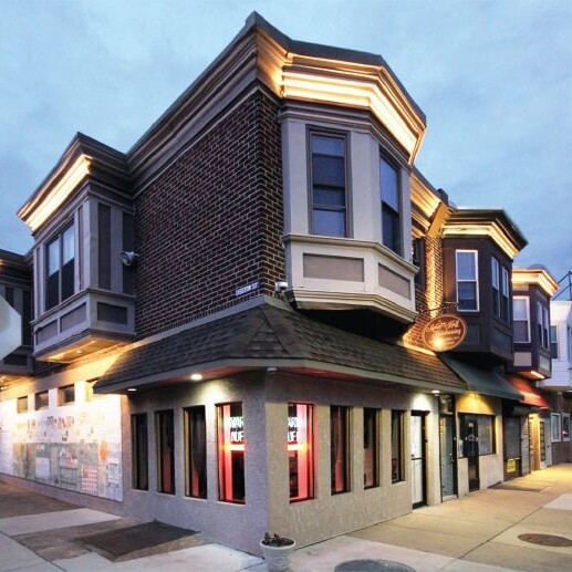 Two-story mixed-use commercial building situated on a corner and illuminated by warm lights.