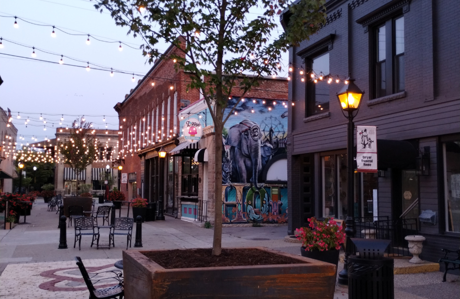 Open pedestrian area with tables, chairs, and strung lights