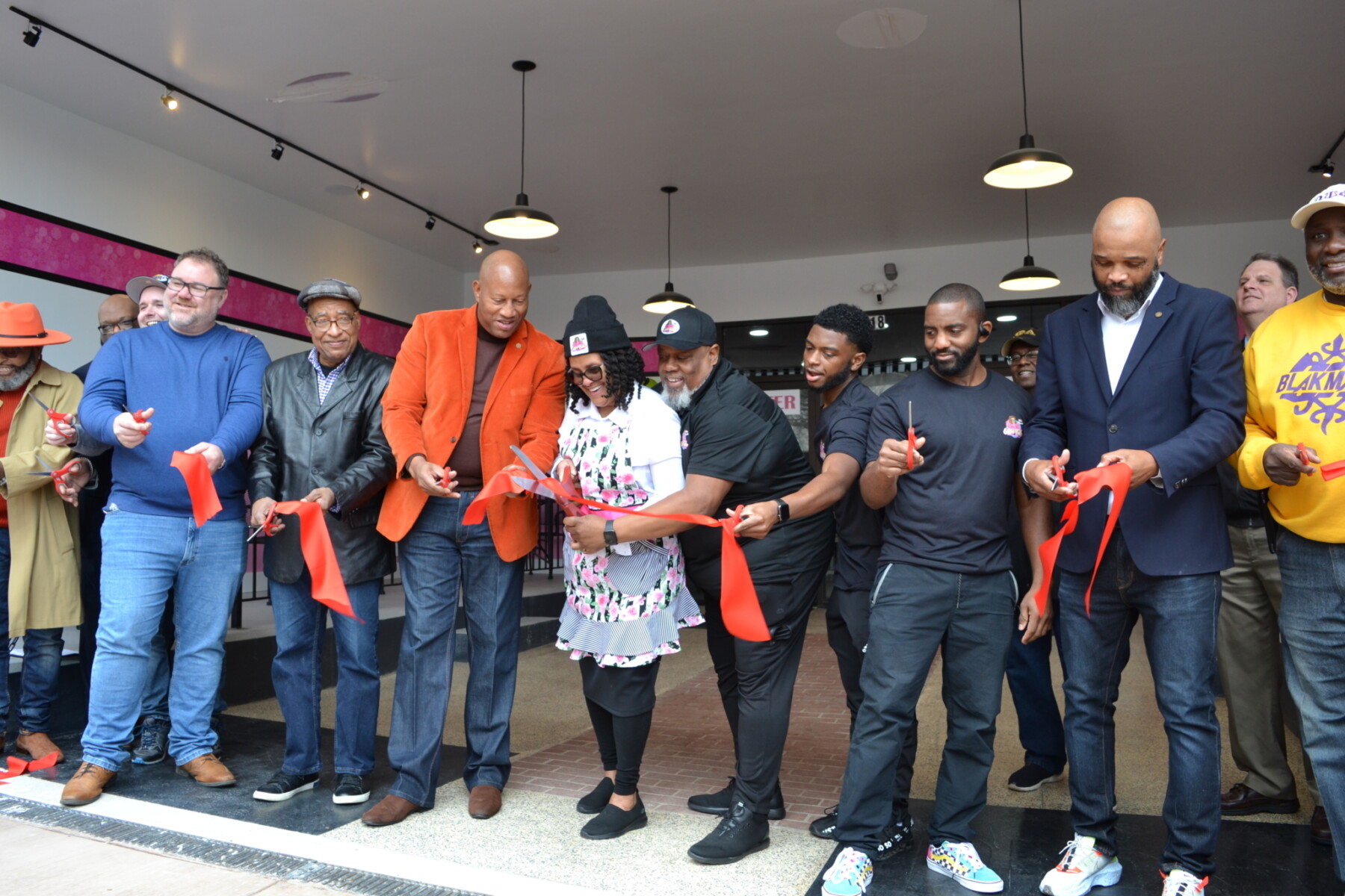 A large group of people participating in a ribbon cutting at a small business