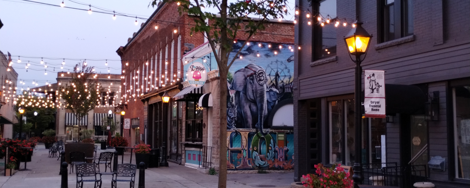 Open pedestrian area with tables, chairs, and strung lights