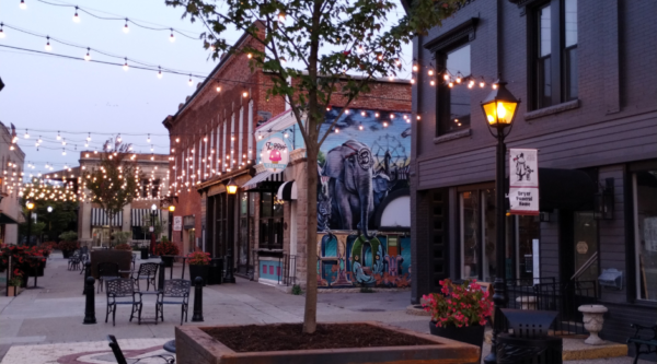 Open pedestrian area with tables, chairs, and strung lights