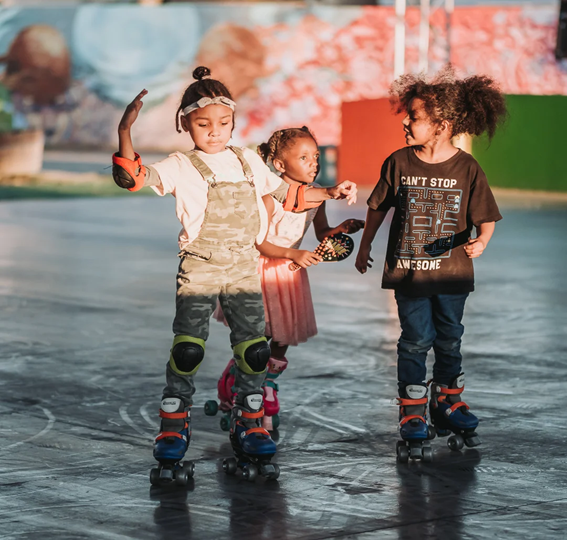 Three children skating on roller skates at an outdoor park