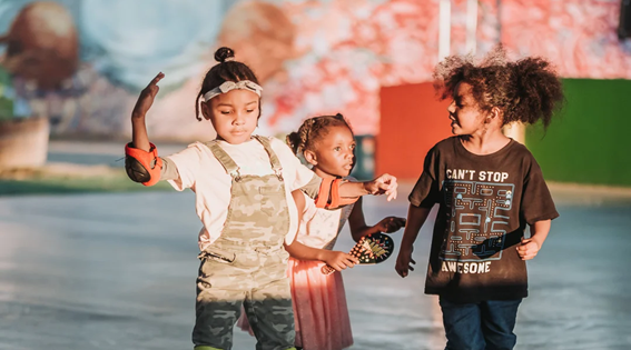 Three children skating on roller skates at an outdoor park