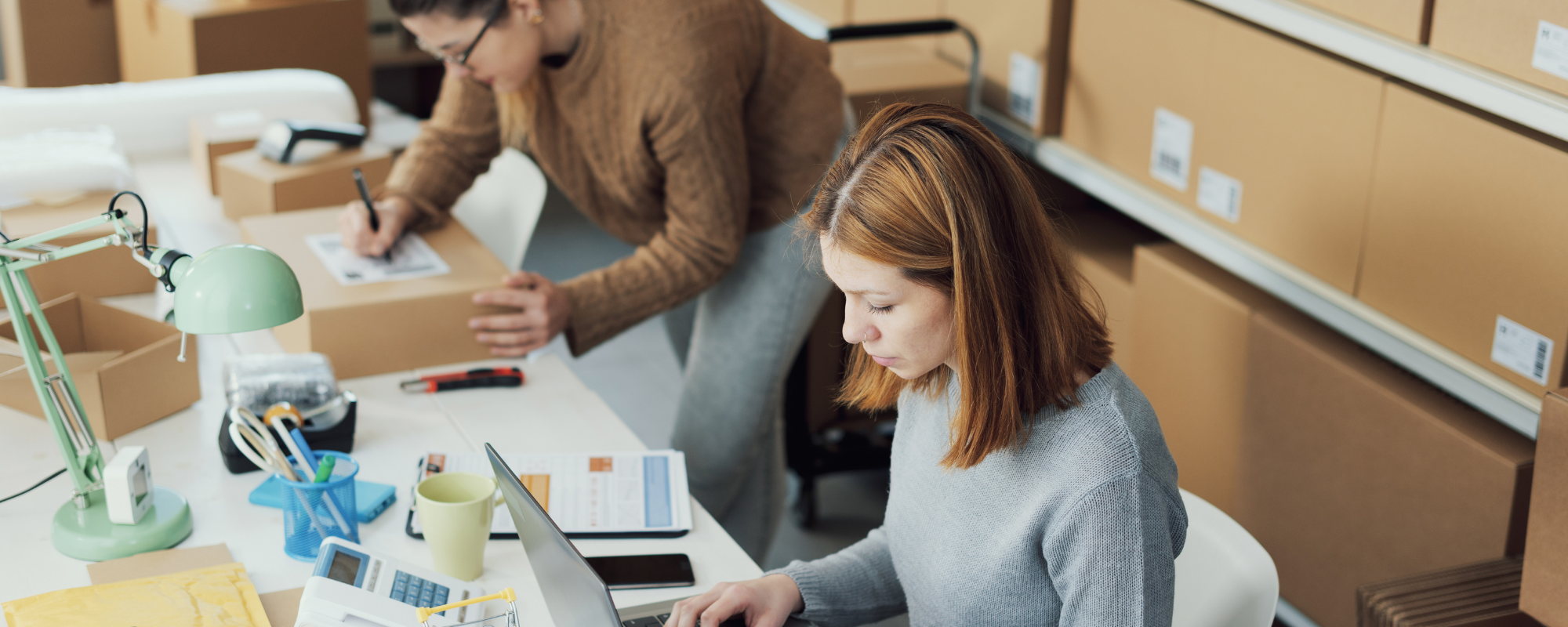 Dos mujeres procesan inventarios y paquetes para una pequeña empresa