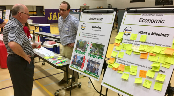 A man participates in a community engagement session by placing post it notes on poster boards